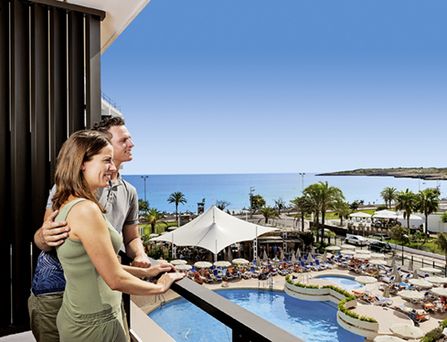 allsun Hotels. Paar steht auf Balkon mit Blick auf das Meer