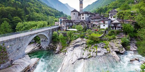 Schweizer Dorf mit Brücke an einem steinigen Fluss 