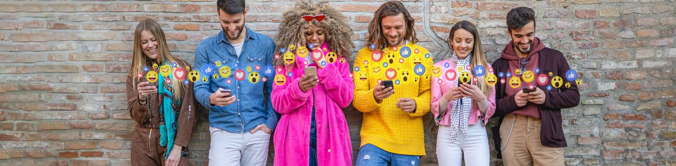 Junge Leute in bunter Kleidung schauen auf Smartphone