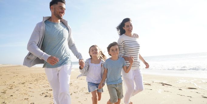 Familienurlaub. Familie läuft Hand in Hand am Strand 