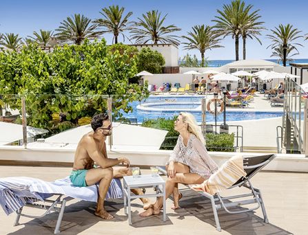 allsun Hotels. Paar unterhält sich auf Liege am Pool 