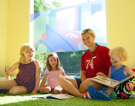 allsun Hotels. Kinderbetreuerin liest Kindern ein Buch vor 
