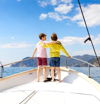 Kroatien. Zwei Jungs schauen Arm in Arm auf einem Boot auf das Meer 