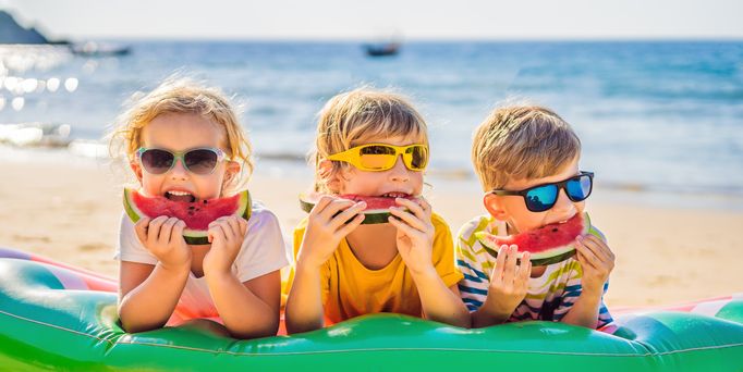 Kinder essen Melone am Strand