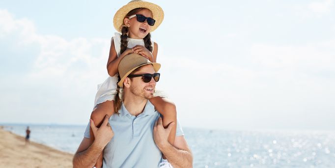 Familienurlaub. Vater trägt Tochter auf den Schultern am Meer 