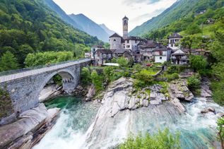 Schweizer Dorf mit Brücke an einem steinigen Fluss 